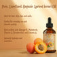 Bottle of apricot kernel oil with apricots on a wooden surface and text about its uses.