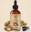 Bottle of Moroccan Argan Oil with dropper and argan nuts on a beige background